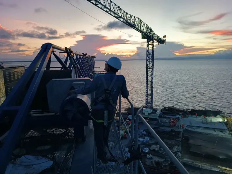 Técnico de Control Crane sobre una torre grúa al atardecer